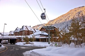 Une station de ski dotée d’un téléphérique, de bâtiments recouverts de neige et offrant une vue imprenable sur les montagnes.