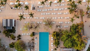 Vue aérienne d’un complexe hôtelier doté d’une plage, d’un espace piscine et de nombreuses chaises longues.