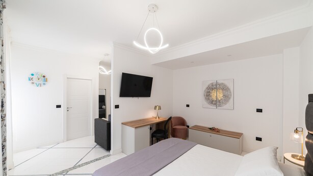 Ett modernt hotellrum med en säng, ett skrivbord, en stol och en platt-TV.