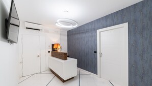 Ett modernt hotellrum med en vit receptionsdisk, en väggmonterad TV, en luftkonditioneringsanläggning och en tapet med mönster.