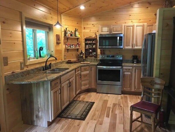 Enjoy cooking in this well-equipped kitchen with a central island, stainless steel appliances, and a comfortable chair.