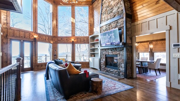 A spacious living area with a stone fireplace, large windows, and a cozy seating area.