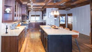 A spacious kitchen with wooden cabinets, granite countertops, and a large island with seating.