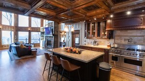 A spacious kitchen with a large island, bar stools, and a stone fireplace.