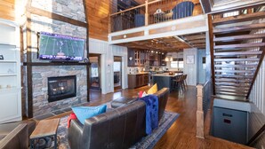 A spacious living area with a fireplace, a stone wall, and a large TV screen.