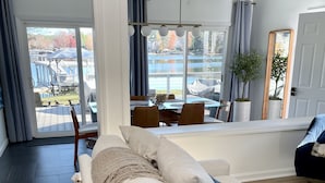 Un salon moderne avec un canapé, une table à manger et une vue sur un lac et une jetée.
