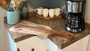 A kitchen counter with a coffee maker, mugs, and a cutting board. - The Arch House (Faribault)
