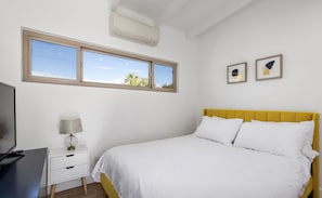 A bedroom with a bed, a nightstand, a lamp, and two framed pictures on the wall. - Private mini oasis steps from El Paseo! (Palm Desert)