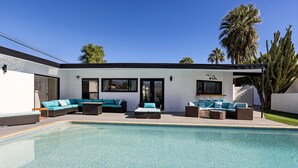 A modern outdoor pool area with a pool, seating, and a building with large windows and doors. - Private mini oasis steps from El Paseo! (Palm Desert)