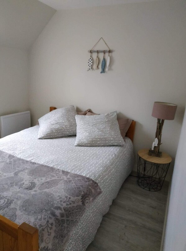 Une chambre à coucher avec un lit, des oreillers, une table de chevet avec une lampe et un élément décoratif mural.