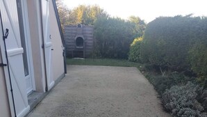 A gravel driveway leading to a building with a small arched entrance. - "Le Gite tranquille" by the sea in Surtainville (Surtainville)