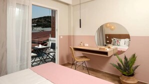 A bedroom with a bed, a desk, a chair, a mirror, and a potted plant. - Salty Colours Apartments in Almyrida (000)