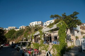 A hillside hotel with outdoor seating and a view of the surrounding buildings. - Salty Colours Apartments in Almyrida (000)