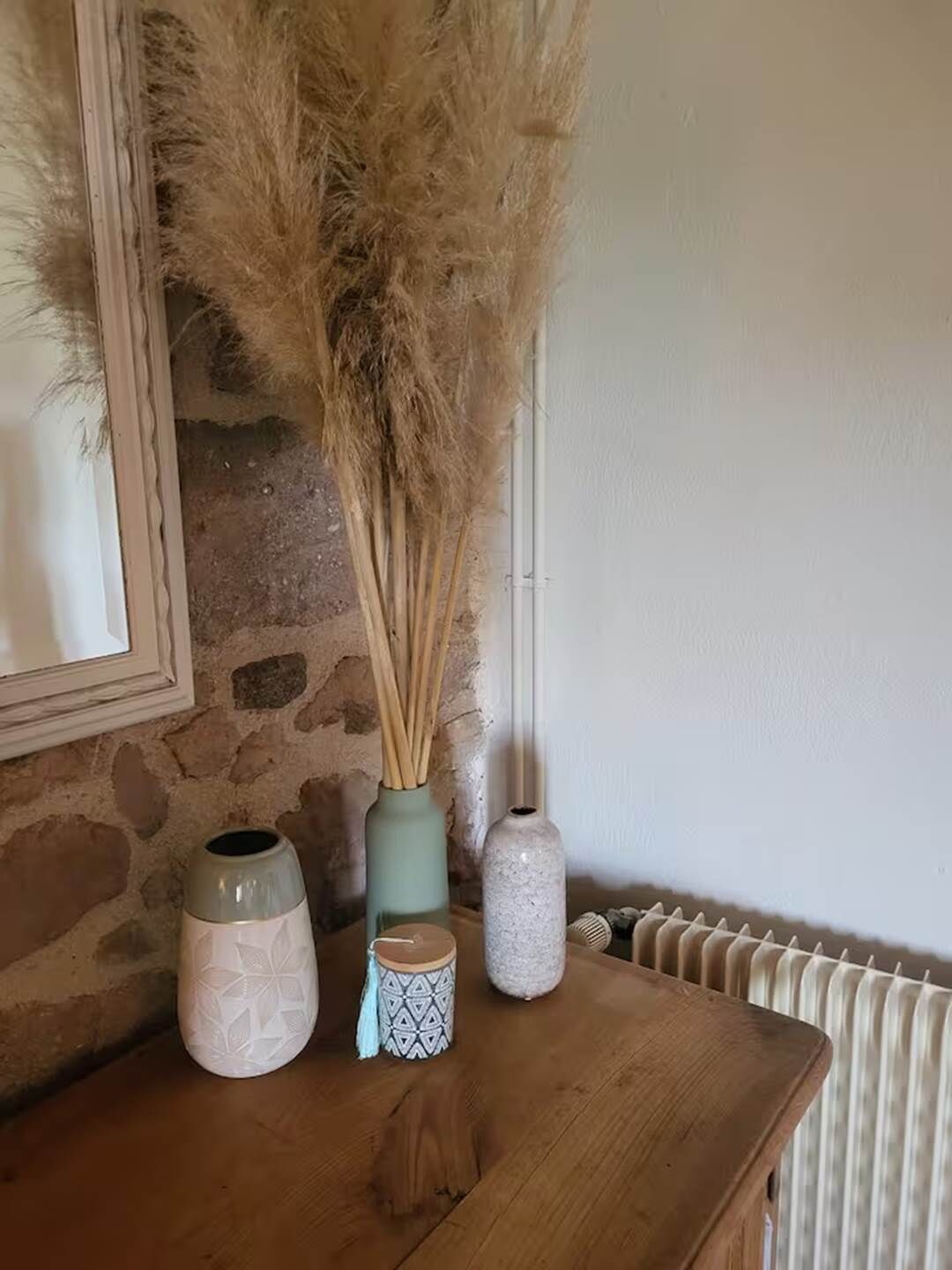 A wooden table with decorative vases and a framed picture on a stone wall.
