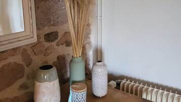 A wooden table with decorative vases and a framed picture on a stone wall.