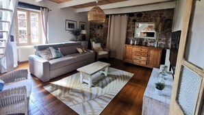 A cozy living room with a wooden ceiling, a stone wall, a sofa, a coffee table, and a cabinet. - The Gîte du Ligal in Najac (Najac)