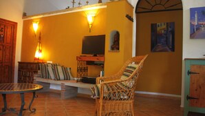 A living room with a wicker chair, a small table, a television, and a bookshelf.