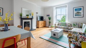 Una sala de estar moderna con chimenea, un sofá, una mesa de comedor y un televisor.