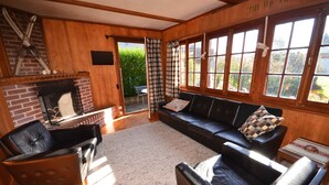 A cozy living room with a fireplace, leather sofas, and large windows offering a view of the garden. - Traditional Chalet with views of the Eiger, Monch & Jungfrau! (Unterseen)