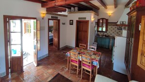 A rustic kitchen with wooden beams, a tiled floor, and a dining area with a table and chairs. - Andalucía; Cádiz; Vejer de la Frontera;  cottage  Finca la Hijuela, casa Encina (Vejer de la Frontera)
