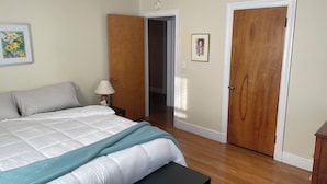 A bedroom with a bed, a bedside table with a lamp, a picture on the wall, and two wooden doors. - Quiet single-level fully furnished house (Bangor)