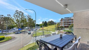 Ein Balkon mit Tisch und Stühlen, mit Blick auf eine belebte Straße und Wohnhäuser.