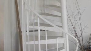 En vit spiraltrappa med en liten avsats där det finns en liten hylla med dekorativa föremål.