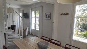 En matplats med ett träbord, röda stolar, en flätad korg och en trappa som leder till ett annat rum.