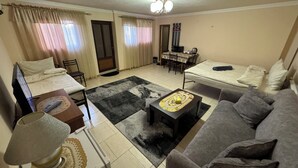A compact living space with a bed, sofa, dining table, and a small kitchen area.