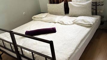Ein Einzelbett mit Holzrahmen, weißer Bettwäsche und einem violetten Handtuch.