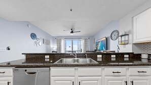 A kitchen with white cabinets, a double sink, and a dishwasher. - Gorgeous Ocean and Bayside View (Miramar Beach)