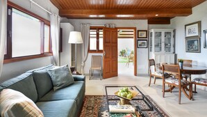 A living room with a sofa, coffee table, and dining area with chairs and a table.