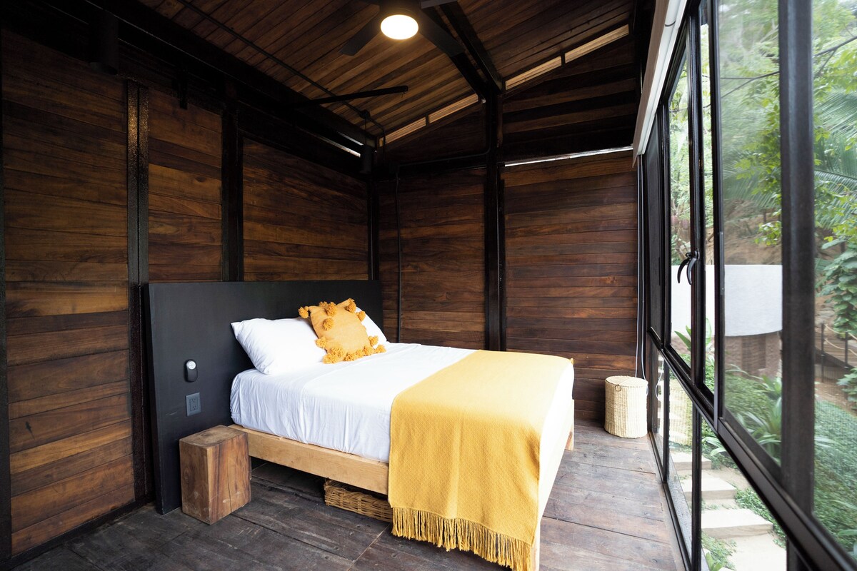 Une pièce en bois avec un lit, une fenêtre et un ventilateur de plafond.