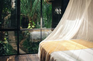 Un dormitorio con cama, ventana y vista a un jardín.
