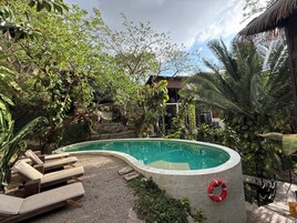 Una piscina al aire libre, sillones reclinables de piscina