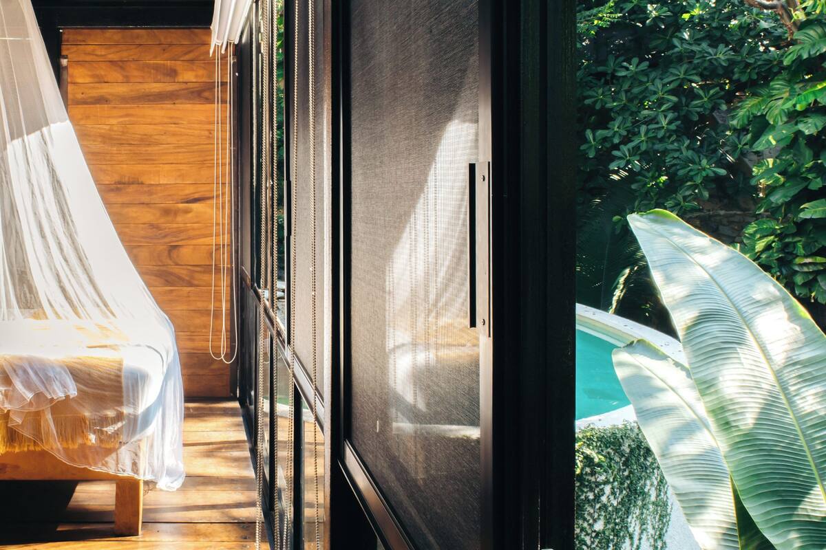 Una habitación con cama, ventana y vistas a zonas verdes.