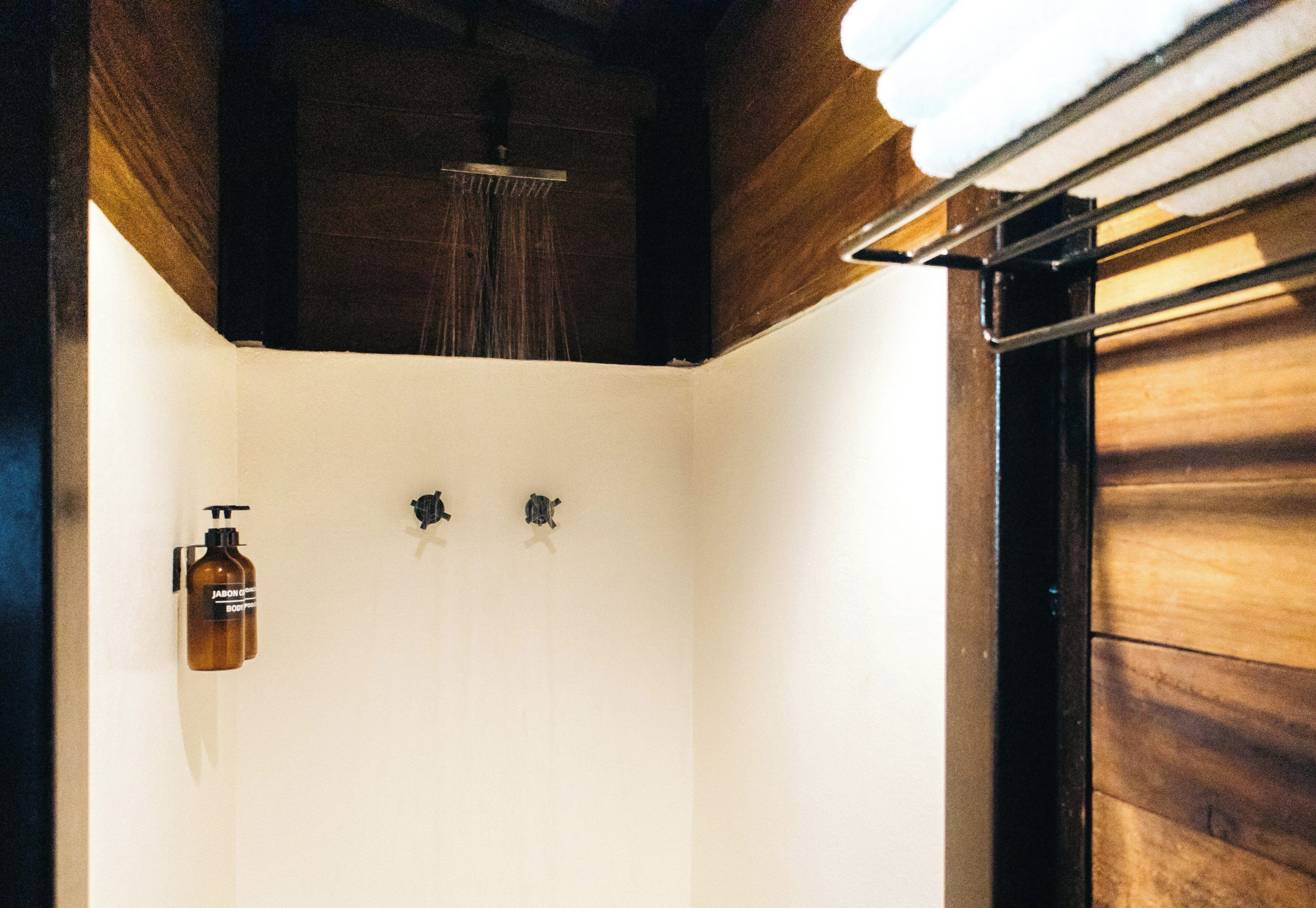 Un baño con techo de madera, una ducha y dos dispensadores de jabón.