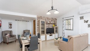 Un saló modern amb zona de menjador, sofà, televisió i llar de foc.