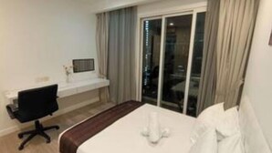 Ein Hotelzimmer mit Bett, Schreibtisch, Stuhl und einem Fenster mit Vorhängen.