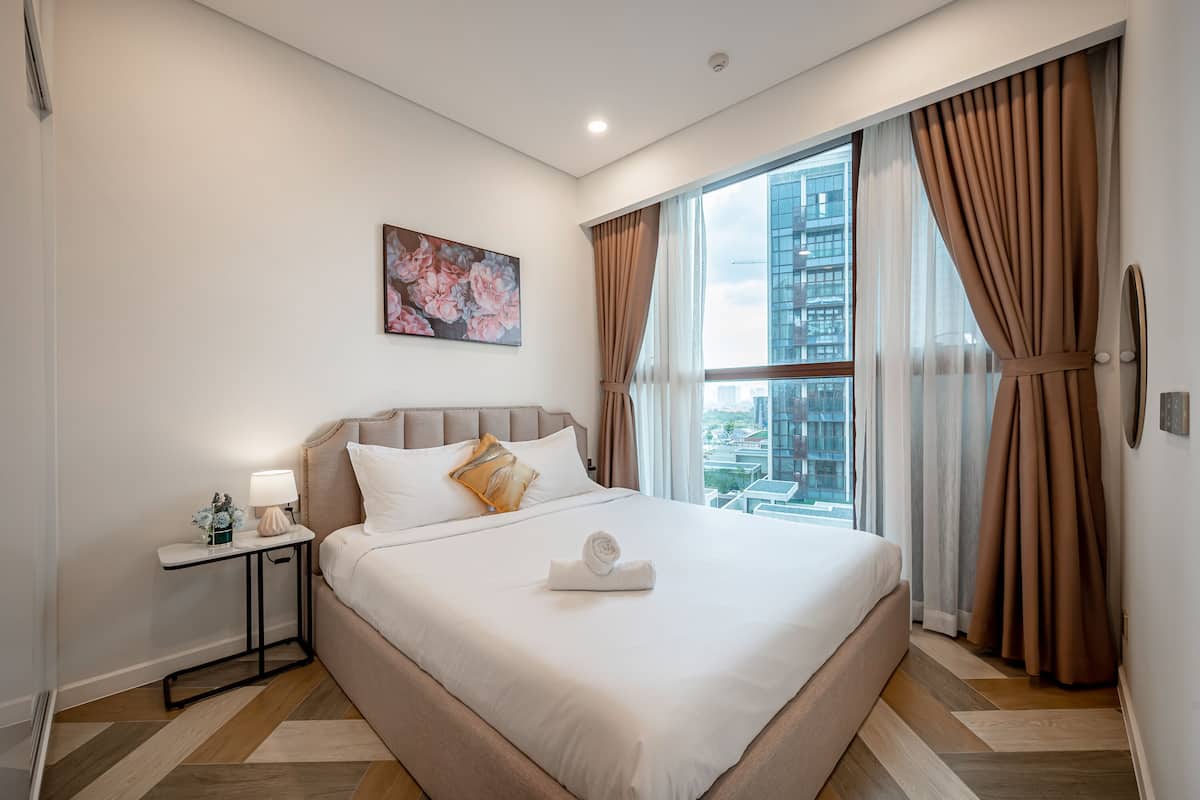 Una habitación de hotel moderna con una cama grande, una mesita de noche, una lámpara y un cuadro en la pared.
