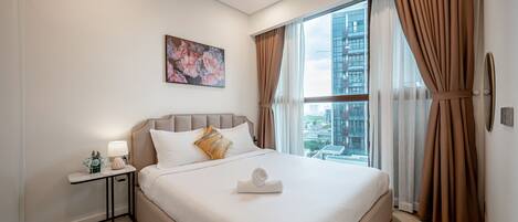 A modern hotel room with a large bed, a nightstand, a lamp, and a painting on the wall.