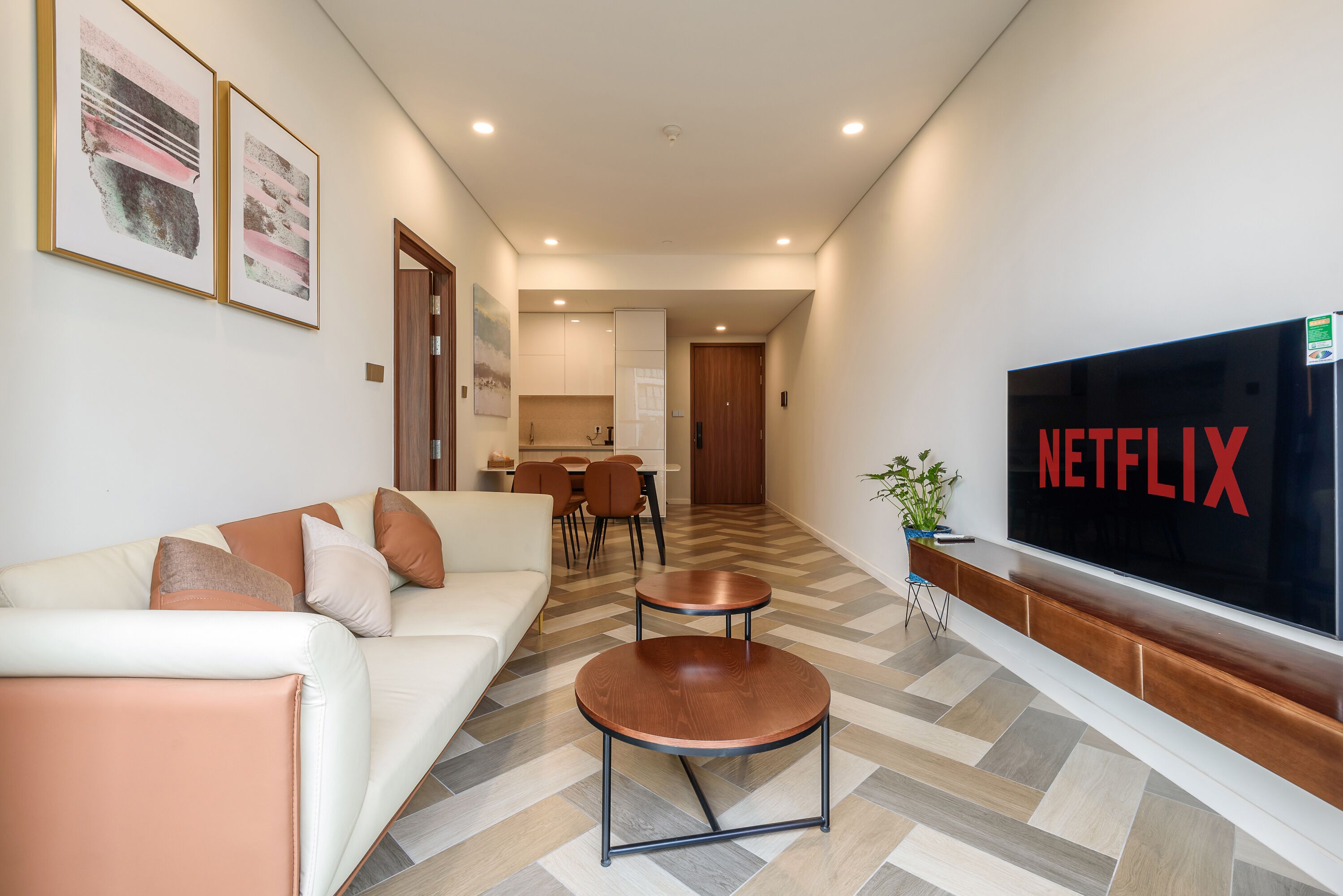 A modern living room with a sofa, coffee table, and a large TV screen displaying the Netflix logo.