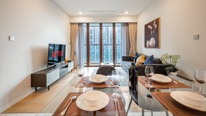 Un salon moderne comprenant un coin repas, un téléviseur à écran plat et une grande fenêtre avec des rideaux.