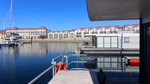 Un port de plaisance avec des bateaux amarrés, un immeuble doté de balcons et un ciel d’un bleu limpide.