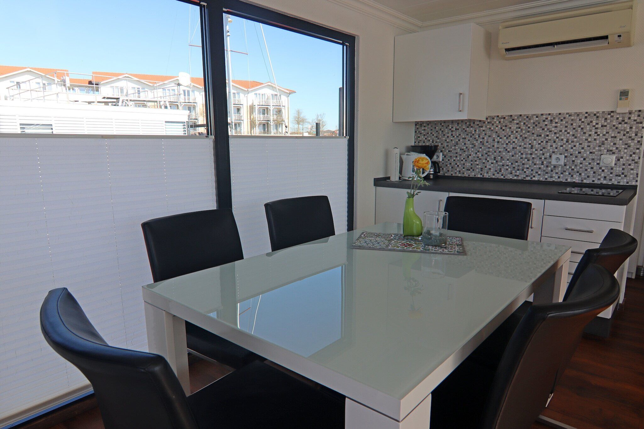 Une cuisine moderne dotée d  ’une grande fenêtre, d’une table à manger avec des chaises, et offrant une vue sur les bâtiments de l’autre côté de l’eau.