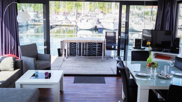 Un salón moderno con pared de vidrio con vistas a un puerto deportivo.