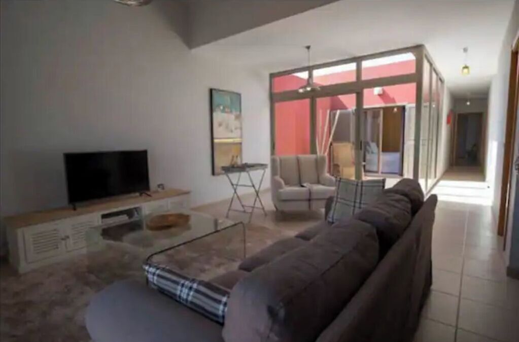 A living room with a sofa, a coffee table, a TV, and a glass partition.