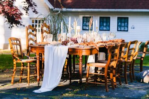 Ein Holzespeisetisch draußen mit Stühlen, Kerzen und Glaswaren.