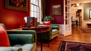 Un salon avec un canapé vert, une table basse en bois et un tapis rouge.