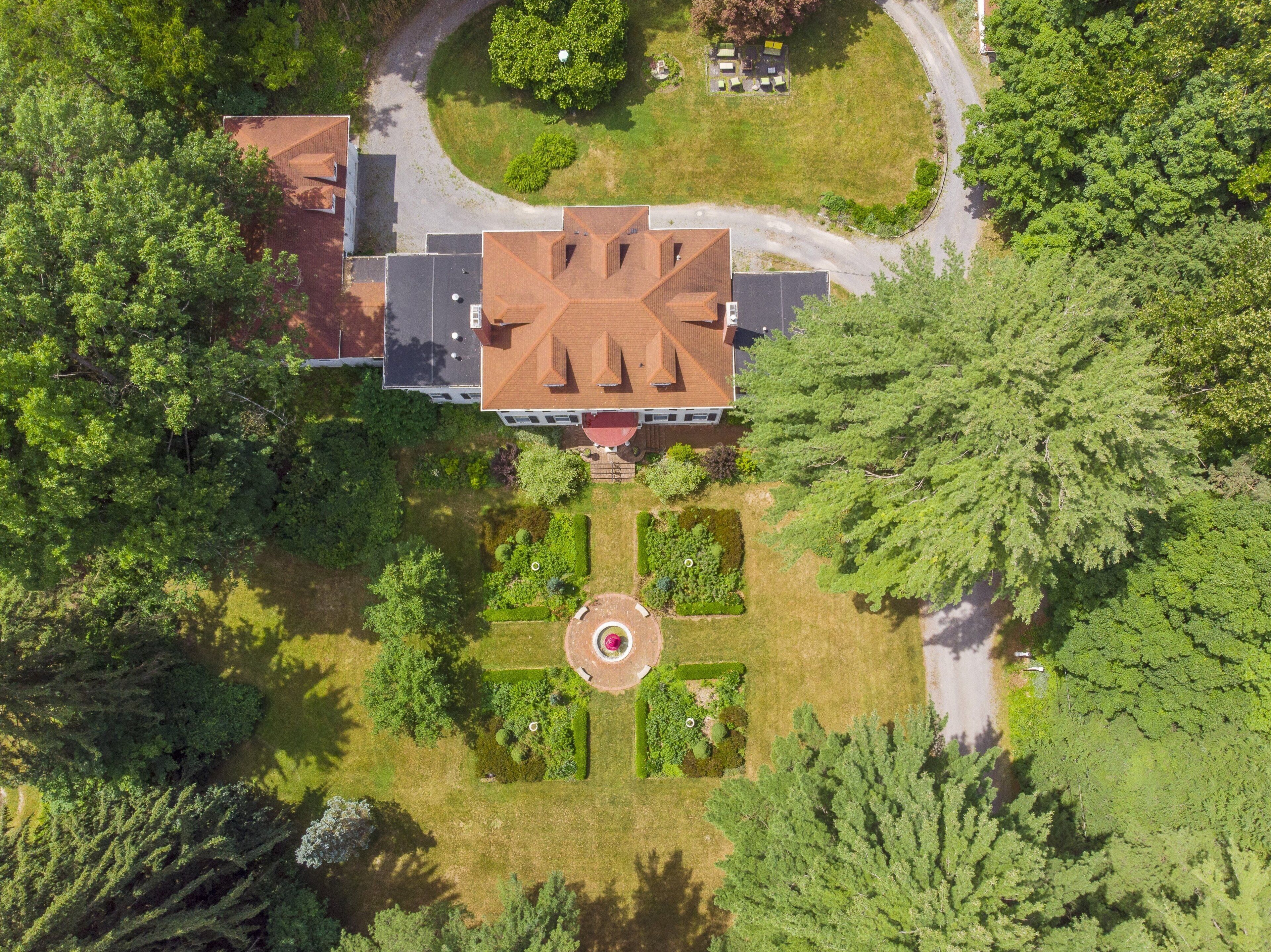 An aerial view of a large building with a symmetrical roof and a central circular garden.